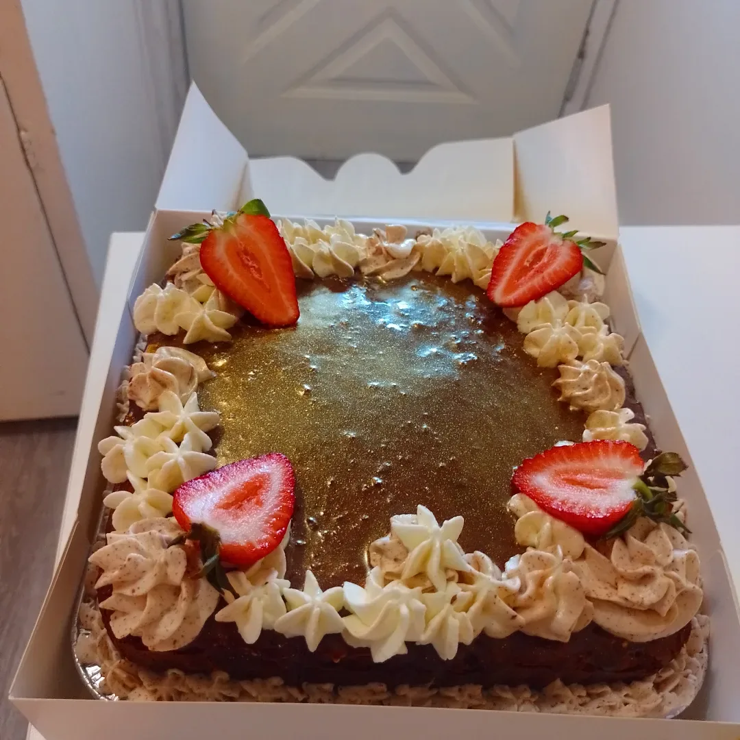 Rectangular chocolate dessert finished with piped cream and strawberries