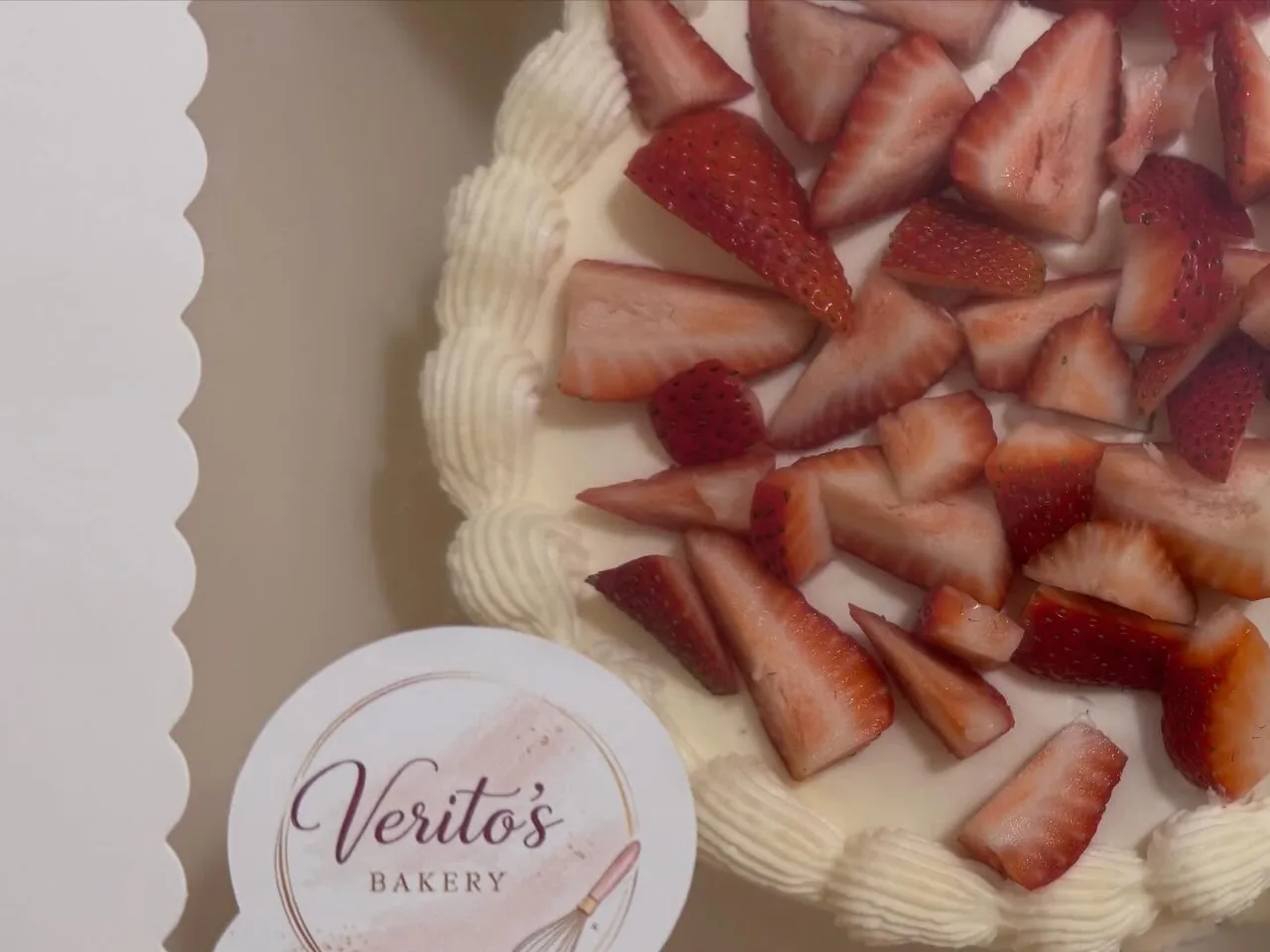 Close view of fresh strawberries and piped cream on a cake finish