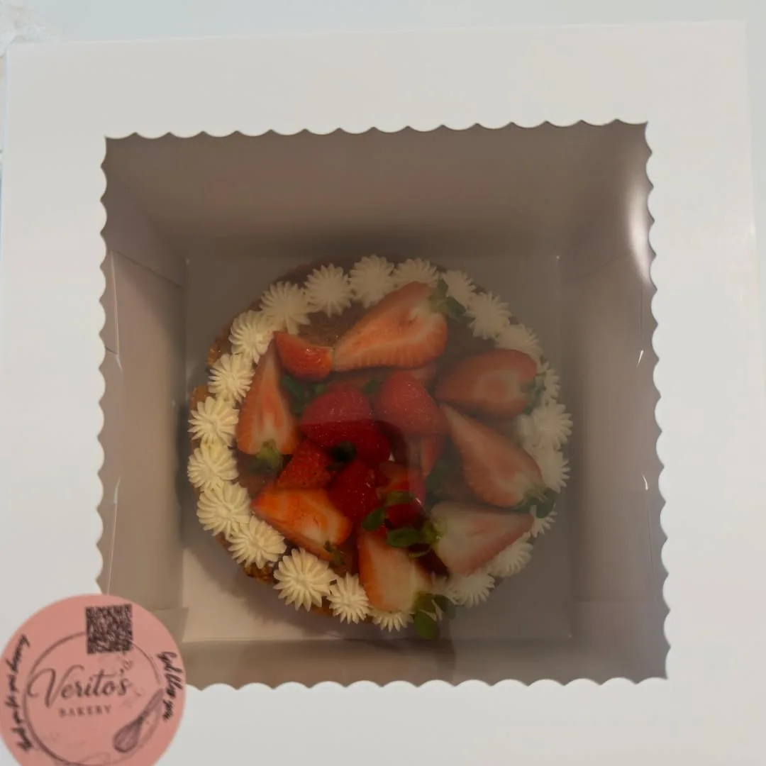 Strawberry-topped celebration cake presented in a Veritos Bakery box